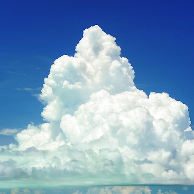 夏の空に大きくそびえ立つ真っ白な積乱雲の写真。青空を背景に、もくもくと盛り上がる雲の塊が塔のように伸びている。下部には層状の雲も重なっている。