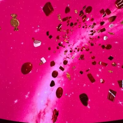 プラネタリウムのドームに映し出された、ピンク色の空からチョコレートが降り注ぐ映像。