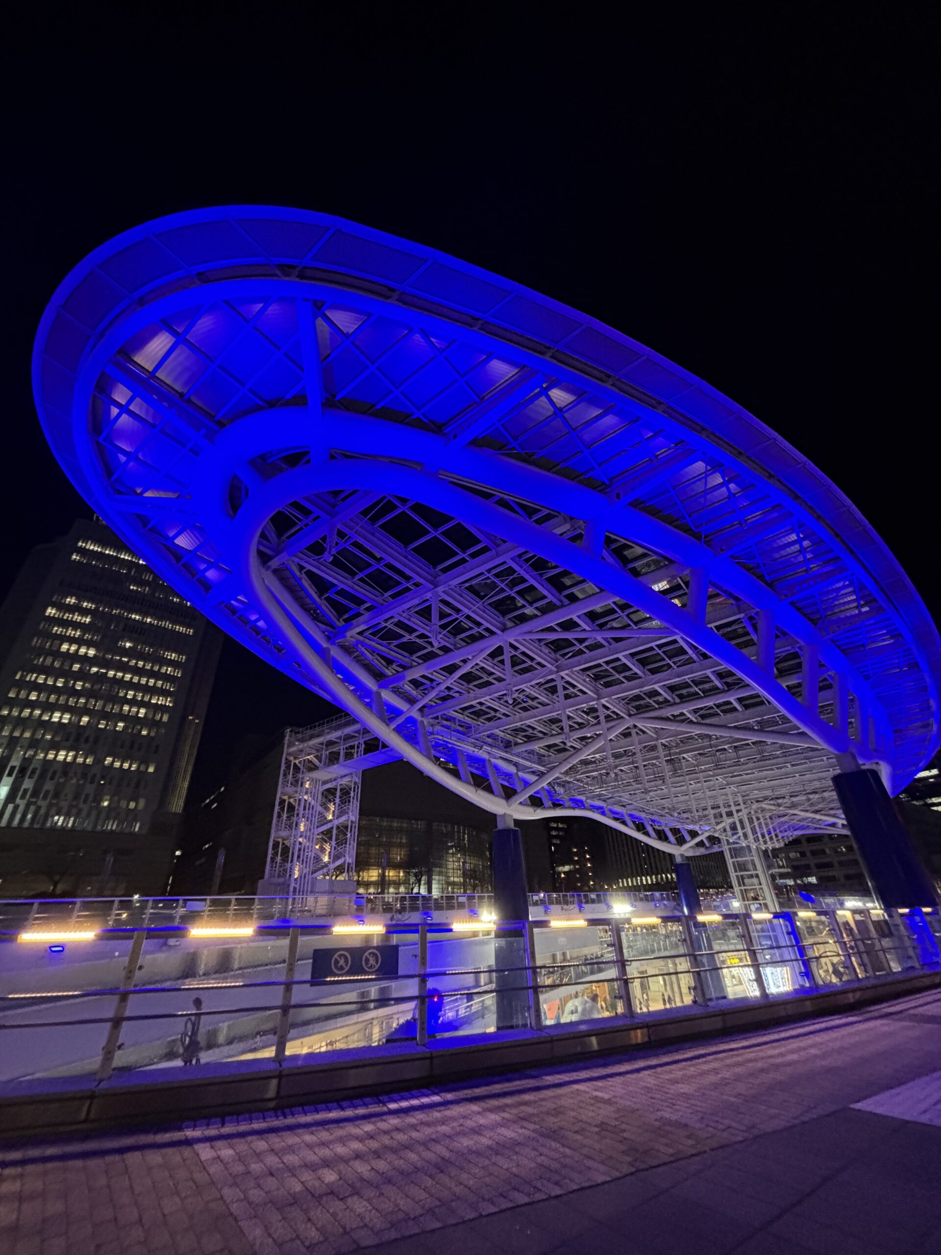 名古屋・オアシス21の屋上構造物が青くライトアップされ、夜空に浮かぶように見える写真。