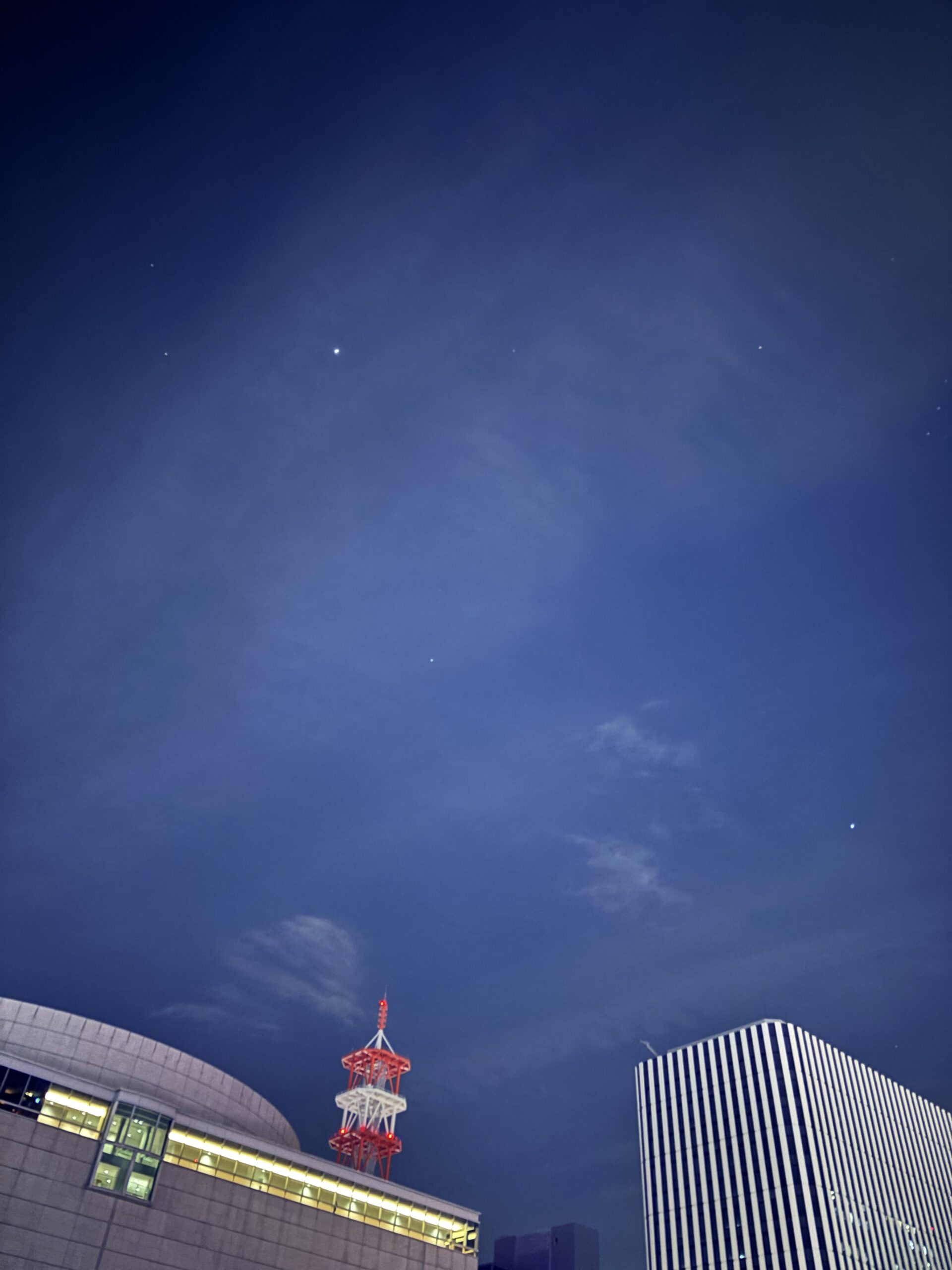 名古屋の夜空に星がいくつか輝き、ビルの屋根や電波塔がシルエットのように写っている写真。
