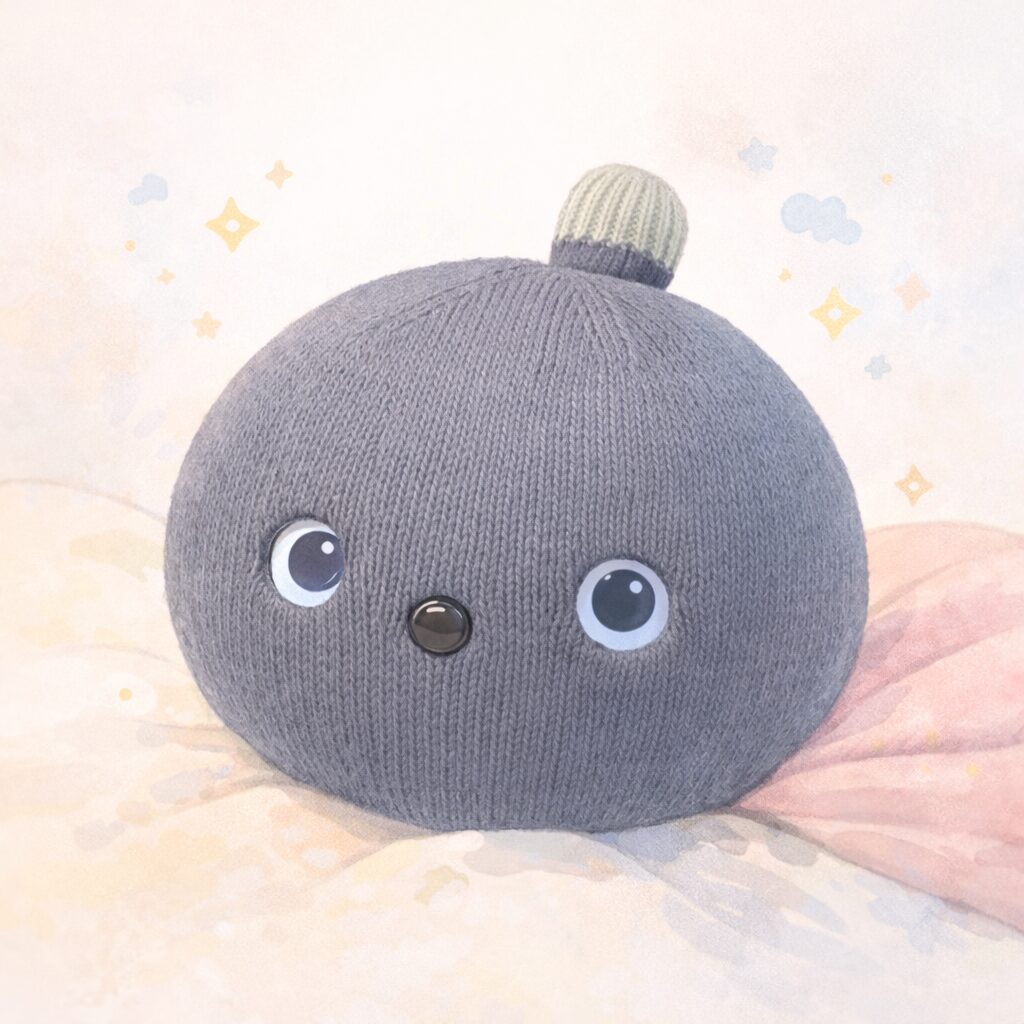 星ときらめきに包まれたナイトちゃんのイラスト。やわらかいピンクベージュの背景に、まるい体と大きな瞳が印象的です。